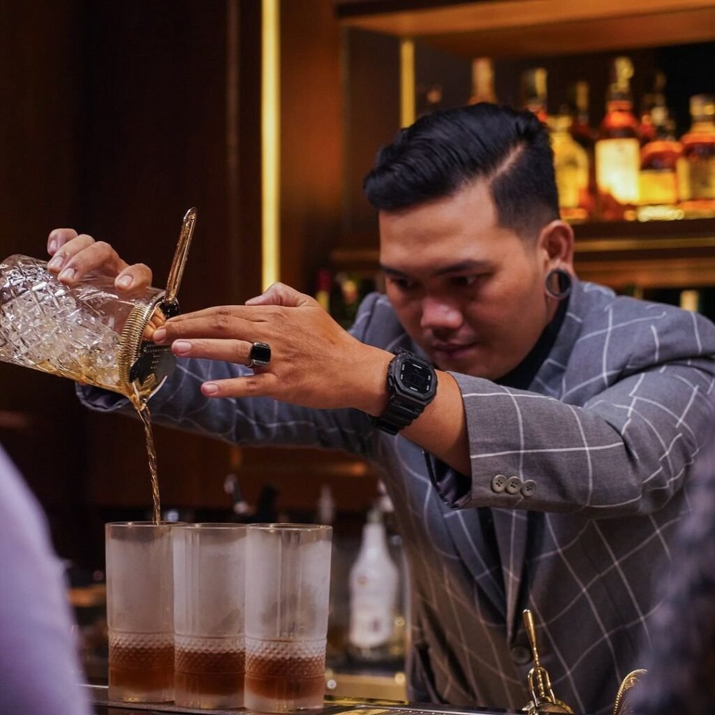 Bartender profesional sedang meracik cocktail spesial di Amber Rooftop Lounge